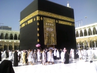 Pilgrims at the door of the Ka'aba. The Hajr ul Aswad is to the left and shielded from the sun by an umberella
